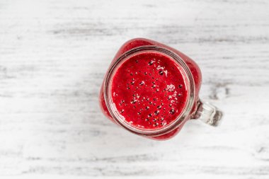 Beyaz masada cam bardakta taze organik kırmızı smoothie, yakın plan, üst manzara. Yaz meyvelerini tazeliyorum. Sağlıklı beslenme kavramı. Böğürtlen, ahududu ve çilekli smoothie