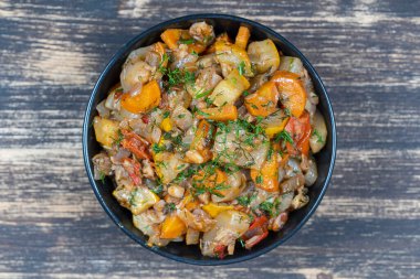 Ahşap masada, siyah bir kasede haşlanmış sebzeler, yakın çekim, üst manzara.