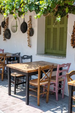 Dışarıdaki küçük kafenin ön manzarası. Beyaz duvarın yanında masa ve boş sandalyeler. Turistik yerler. Tipik Akdeniz restoranı, yazın tatil yapılan bir yer. Kos Adası, Yunanistan