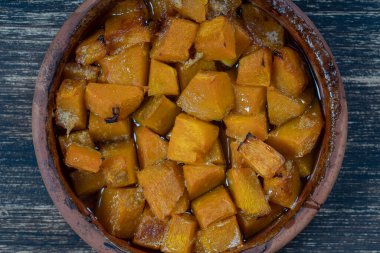 Ballı fırında sarı balkabağı, zeytinyağı ve ahşap masadaki baharatlar. Vejetaryen yemeği. Kapat.