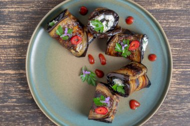 Patlıcan ruloları keçi peyniri ile doldurulmuş yeşil maydanoz ve çiçeklerle süslenmiş. Üst görünüm