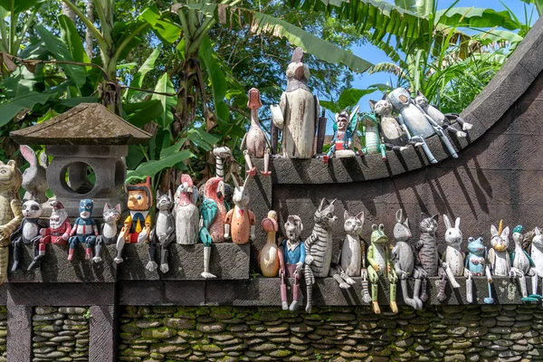 Old wooden souvenirs toys on the stone fence near the doll shop in Ubud, Bali island, Indonesia. Close up