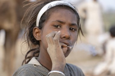 PUSHKAR, INDIA - 14 Kasım 2018: Çölde sigara içen Hintli genç kız Thar zamanında Pushkar Camel Mela kutsal şehir Pushkar, Rajasthan, Hindistan, yakın plan portresi