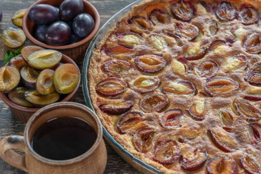 Ev yapımı organik erikli turta yenmeye hazır. Eski ahşap arka planda erik turtası ve fincan sıcak çay, kapatın.