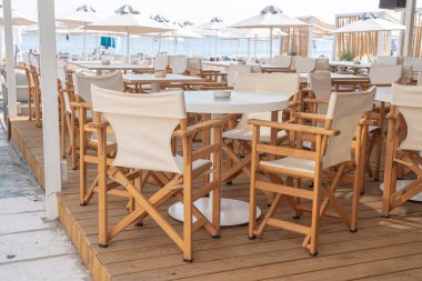 Yunanistan 'ın Kos Adası sahilindeki restoranda boş masa ve sandalyeler. Deniz kenarındaki sahil kafeteryasında, açık havada. Seyahat ve tatil kavramı