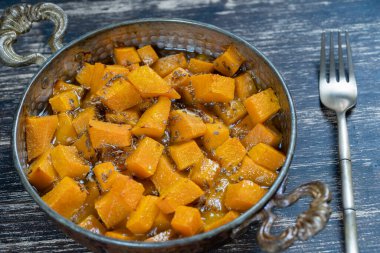 Bal, anason, zeytinyağı ve ahşap masadaki baharatlarla pişirilmiş sarı balkabağı. Vejetaryen yemeği. Kapat.