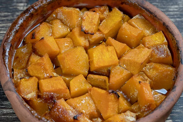 Ballı fırında sarı balkabağı, zeytinyağı ve ahşap masadaki baharatlar. Vejetaryen yemeği. Kapat.