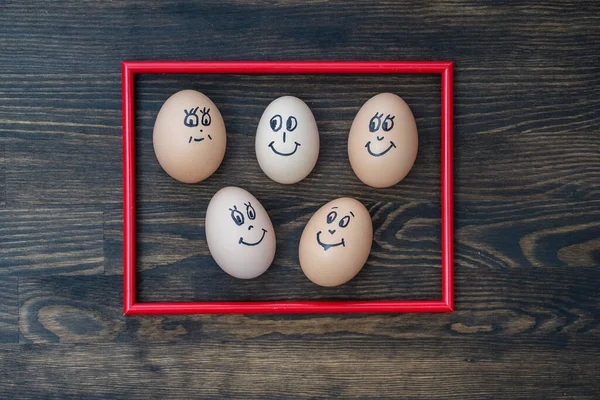 Imagem Moldura Vermelha Muitos Ovos Engraçados Sorrindo Fundo Parede Madeira — Fotografia de Stock