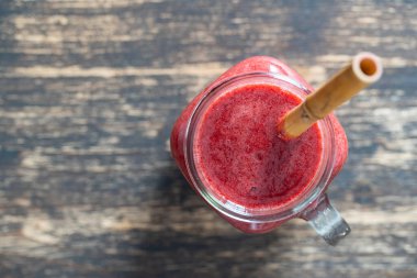 Cam kavanozda taze böğürtlen püresi ve ahşap arka planda bambu kamışı. Üst Manzara, kapat, kopyala alanı. Sağlıklı gıda konsepti