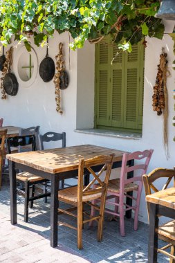 Dışarıdaki küçük kafenin ön manzarası. Beyaz duvarın yanında masa ve boş sandalyeler. Turistik yerler. Tipik Akdeniz restoranı, yazın tatil yapılan bir yer. Kos Adası, Yunanistan