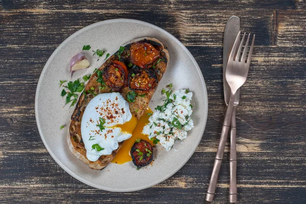 Kızarmış kırmızı domatesli haşlanmış yumurta, tabakta sarımsak ve süzme peynir, yakın çekim, üst manzara
