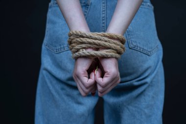 Siyah arka planda elleri bağlı genç bir kız. Kadın şiddeti kavramı. Kapat.