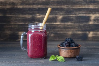 Ahşap arka plandaki cam kavanozda taze böğürtlen smoothie, yakın çekim. Sağlıklı gıda konsepti