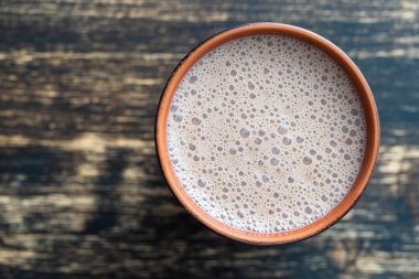Ahşap arka planda seramik bardak çikolatalı milkshake. Üst görünüm, kapat, boşluğu kopyala