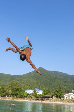 KOH PHANGAN, THAILAND - 18 Mayıs 2019: Mutlu Taylandlılar Tayland 'daki Koh Phangan adasının sahilindeki bir sıçrama tahtasından atlıyorlar