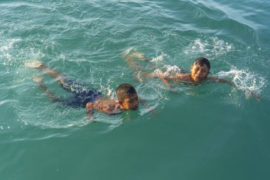 KOH PHANGAN, THAILAND - 18 Mayıs 2019: 2 mutlu Taylandlı çocuk Tayland 'daki Koh Phangan adasının sahilinde deniz suyunda yüzüyor