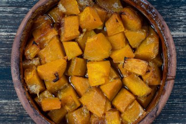 Ballı fırında sarı balkabağı, zeytinyağı ve ahşap masadaki baharatlar. Vejetaryen yemeği. Kapat.