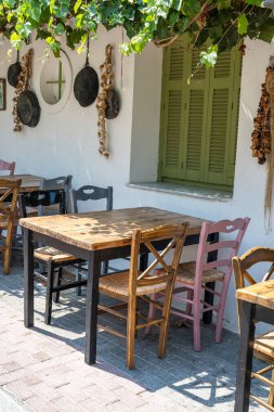 Dışarıdaki küçük kafenin ön manzarası. Beyaz duvarın yanında masa ve boş sandalyeler. Turistik yerler. Tipik Akdeniz restoranı, yazın tatil yapılan bir yer. Kos Adası, Yunanistan