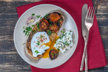 Kızarmış kırmızı domatesli haşlanmış yumurta, tabakta sarımsak ve süzme peynir, yakın çekim, üst manzara
