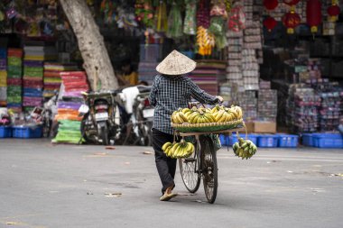 Motosikletli Vietnamlı kadın muz satıyor. Hanoi, Vietnam 'daki eski bir kasabanın sokak yiyecek pazarında.