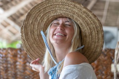 Tropikal bir plajda hasır şapkalı mutlu bir genç kadın, yakın plan portre, Zanzibar adası, Tanzanya, Doğu Afrika. Seyahat ve tatil kavramı