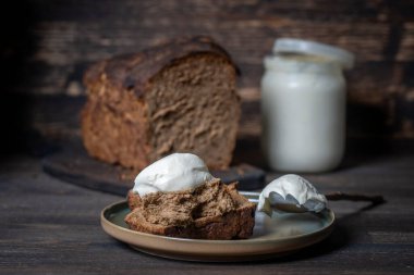 Ev yapımı ekmek ve beyaz ekşi krema ahşap masada, yakın çekim.