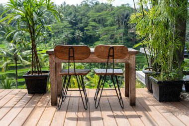 Bali, Endonezya 'daki pirinç teraslarının yanındaki boş tropikal kafede tahta masa ve sandalyeler. Kapatın.