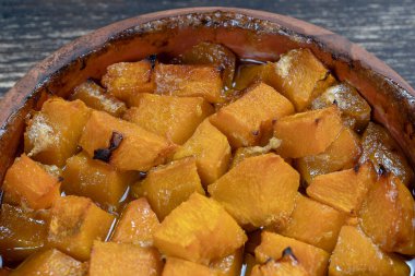 Ballı fırında sarı balkabağı, zeytinyağı ve ahşap masadaki baharatlar. Vejetaryen yemeği. Kapat.