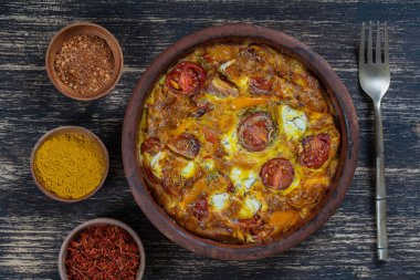 Sebzeli frittata ile seramik kase, basit vejetaryen yemeği. Tahta masada domates, biber, soğan ve peynirli frittata, yakın çekim. İtalyan omleti, üst manzara.