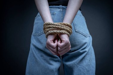 Siyah arka planda elleri bağlı genç bir kız. Kadın şiddeti kavramı. Kapat.