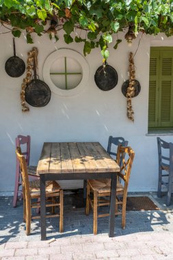 Dışarıdaki küçük kafenin ön manzarası. Beyaz duvarın yanında masa ve boş sandalyeler. Turistik yerler. Tipik Akdeniz restoranı, yazın tatil yapılan bir yer. Kos Adası, Yunanistan