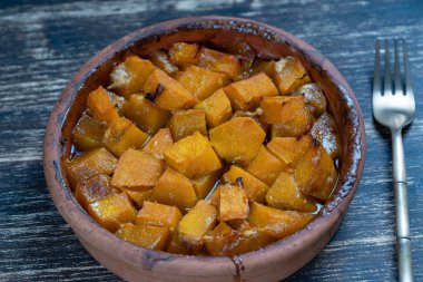 Ballı fırında sarı balkabağı, zeytinyağı ve ahşap masadaki baharatlar. Vejetaryen yemeği. Kapat.