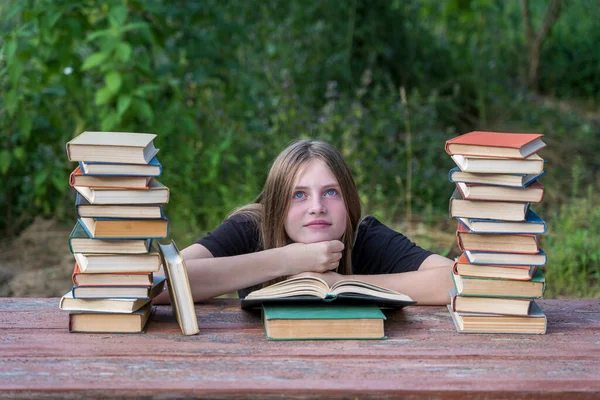Mladá Dívka Čte Knihu Sny Zahradě Dřevěného Stolu Hromadou Knih — Stock fotografie