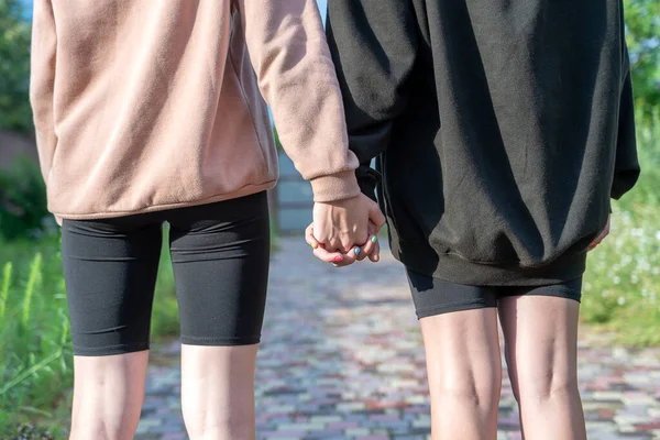 Couple girls hands on the street in nature, close up
