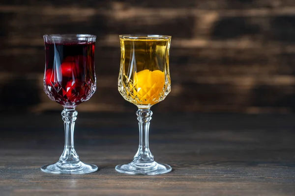 木製の背景にワインクリスタルグラスで赤桜と黄色の桜梅の自家製の色合い ウクライナ クローズアップ コピースペース ベリーアルコール飲料のコンセプト — ストック写真