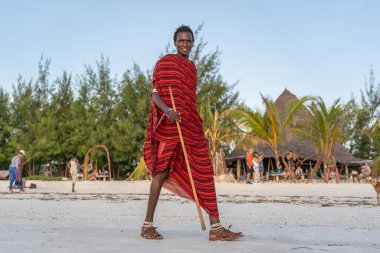Zanzibar, Tanzanya - Aralık 07, 2019: Geleneksel kıyafetler giymiş Afrikalı adam masai Zanzibar adasının kumsalında yürüyor, Tanzanya, Doğu Afrika, kapatın