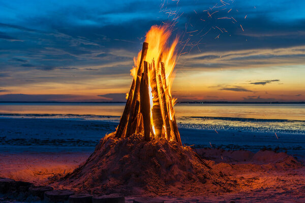 The big fire burns against the background of the night sky near sea on the island of Zanzibar, Tanzania, East Africa, close up. Bright flame. A bonfire in the evening.