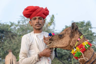 PUSHKAR, INDIA - 15 Kasım 2018: Hindistan 'ın kutsal şehri Pushkar, Rajasthan yakınlarındaki Pushkar Camel Mela sırasında çöldeki Hintli adam. Bu fuar dünyanın en büyük deve ticaret fuarı..