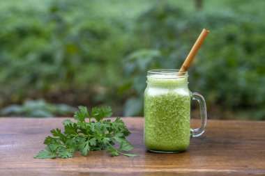Yeşil maydanoz, avokado, bal ve muz. Bir bahçe kafesinde, ahşap bir masada, cam bardakta. Yakın plan. Sağlıklı gıda konsepti