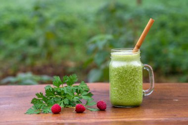 Yeşil maydanoz, avokado, bal ve muz. Bir bahçe kafesinde, ahşap bir masada, cam bardakta. Yakın plan. Sağlıklı gıda konsepti