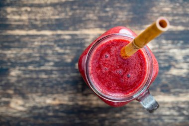 Cam kavanozda taze böğürtlen püresi ve ahşap arka planda bambu kamışı. Üst Manzara, kapat, kopyala alanı. Sağlıklı gıda konsepti