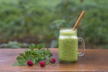 Yeşil maydanoz, avokado, bal ve muz. Bir bahçe kafesinde, ahşap bir masada, cam bardakta. Yakın plan. Sağlıklı gıda konsepti
