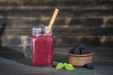Ahşap arka plandaki cam kavanozda taze böğürtlen smoothie, yakın çekim. Sağlıklı gıda konsepti