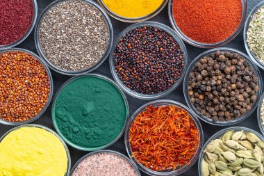Arka planda farklı baharatlar ve otlar, yakın plan, üst manzara. Renkli baharatlar, tohumlar ve yemek pişirmek için bitkiler.