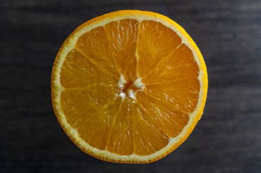 Dilimlenmiş olgun portakalı kapat, makro. Ahşap arka planda sarı turuncu yüzey. Üst görünüm