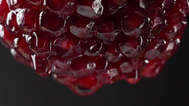 黒い背景の果実の半分から落ちる赤いザクロジュース マクロ写真 テクスチャ 新鮮なフルーツ クローズアップ — ストック動画
