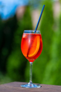 Aperol spritz kokteyli ve şarap kadehi, doğal bir arka plan. Klasik İtalyan aperatifi aperatif sprey kokteyli. Bir dilim portakallı. Kapatın. Yaz güneşli ferahlatıcı içecek