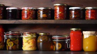 Kışın tüketim için mahzendeki ahşap raflarda cam kavanozlarda pek çok konserve yiyecek var. Kapatın. Gıda korunumu. Renkli turşu ve mayalanmış sebze kavanozları, bal, reçel ve diğer ürünler.