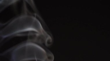 Siyah arka planda beyaz duman yavaş çekimde. Beyaz buhar döner ve yükselir.