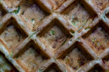Kabağın arka planı ve dokusu ve waffle makinesiyle yapılmış otlu waffle, yakın plan, üst manzara. Yemek için lezzetli kabaklı waffle.
